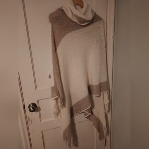 Two-tone fringed poncho with an asymmetrical hem, fringe and a cowl neck. 